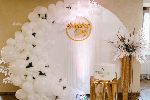 拱门上装饰着白色气球、鲜花和绿色植物。金色的秋天装饰在宴会的宴会区。奢华仪式中的装饰。结婚礼盒里的钱。图片下载