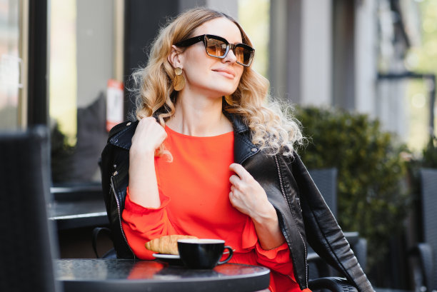 非常漂亮的年轻女子，坐在咖啡馆喝咖啡或茶，街景图片下载