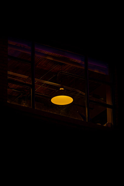 黄色吸顶灯从窗户在晚上和黑暗的背景图片下载