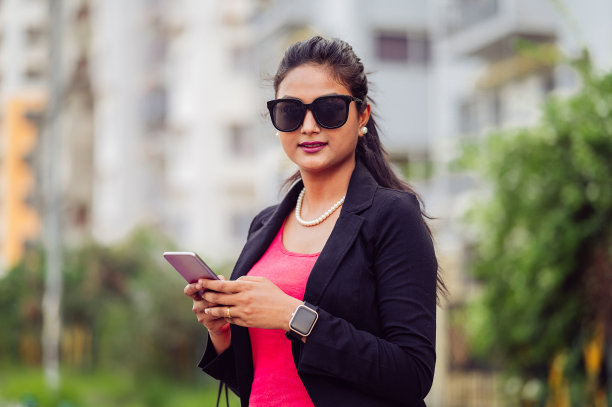 快乐的年轻女子使用智能手机。图片下载
