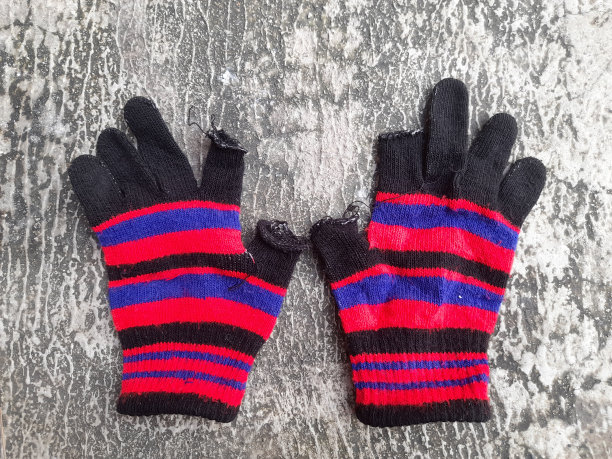 彩色针织手套制成的羊毛纱线在街道纹理背景。图片下载