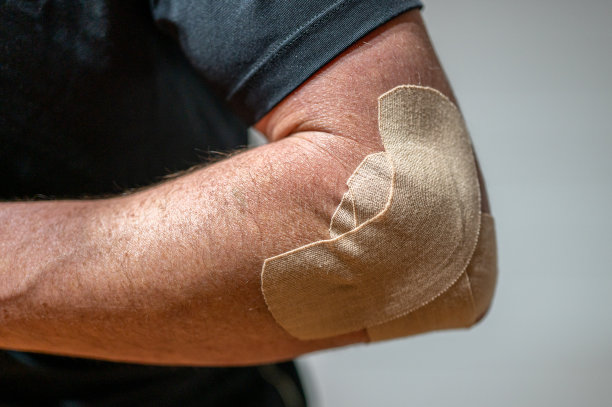 用理疗胶带治疗肘部疼痛。“网球肘”在骨科病房用弹性绷带包扎。积极运动的人健康康复的概念形象。图片下载