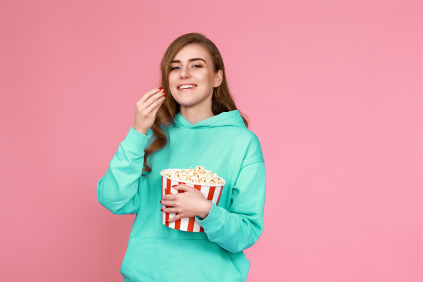 穿着运动衫的女人在看电影，吃爆米花图片下载