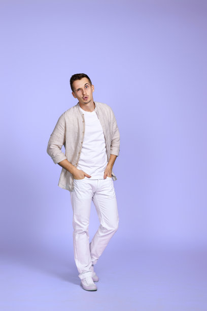 穿着休闲衬衫的男子在紫色背景上摆姿势。图片下载