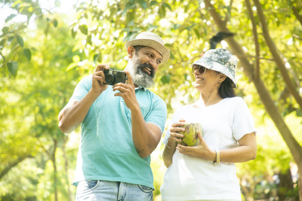 快乐的印度老夫妇游客拿着相机在夏日公园一起拍照。成熟的人旅游度假。图片下载