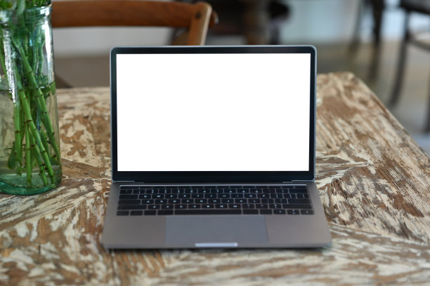 在质朴的木桌上模拟笔记本电脑和玻璃罐。白色屏幕为您的广告设计。图片下载