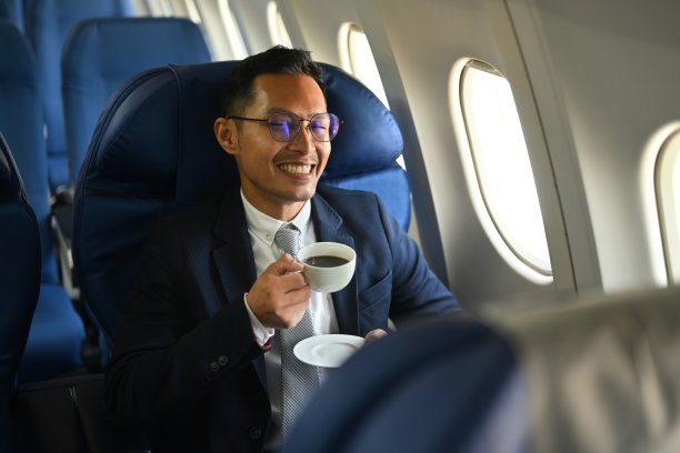 商务旅客满意地坐在舒适的座位上喝着热咖啡。图片下载