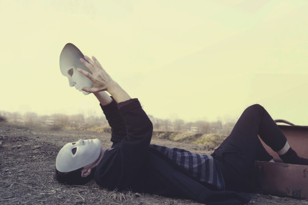 带面具的男人看着自己的另一个面具，自省的概念图片下载