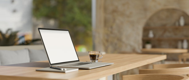 在最小的斯堪的纳维亚咖啡店里，木制桌子上的笔记本电脑模型和咖啡杯图片下载