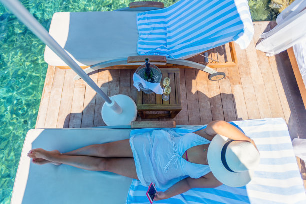 沙滩日光浴上的女人。她正在用手机。图片下载