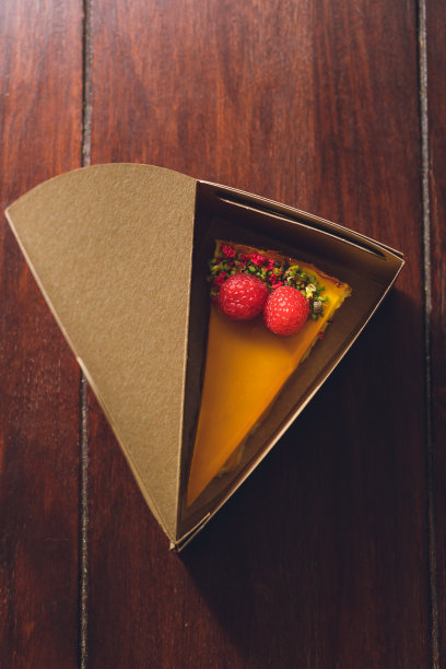 俯视图的芒果芝士蛋糕与覆盆子在蛋糕盒图片下载