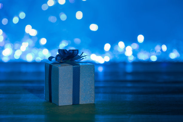 礼盒系在一个发光的花环蓝色背景的丝带。图片下载