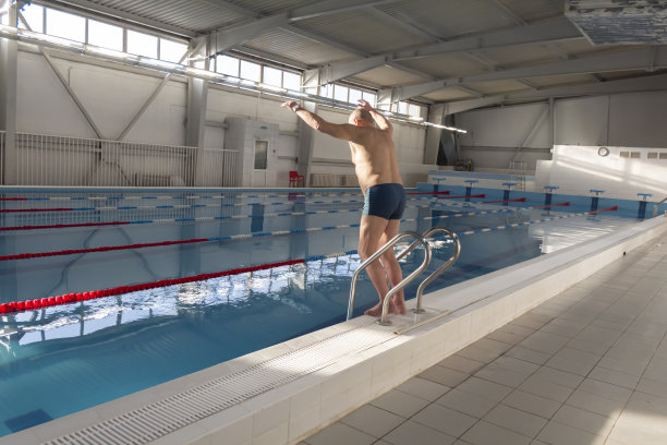 一位老人在一个退役的体育中心的游泳池里积极地从事游泳和运动。图片下载
