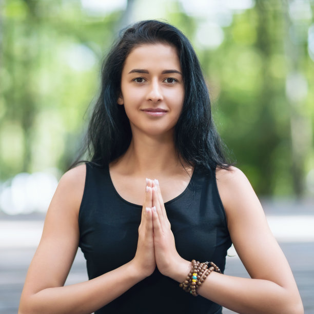 年轻美丽的女子在公园练习瑜伽表演合十礼的肖像，教练看着相机图片下载