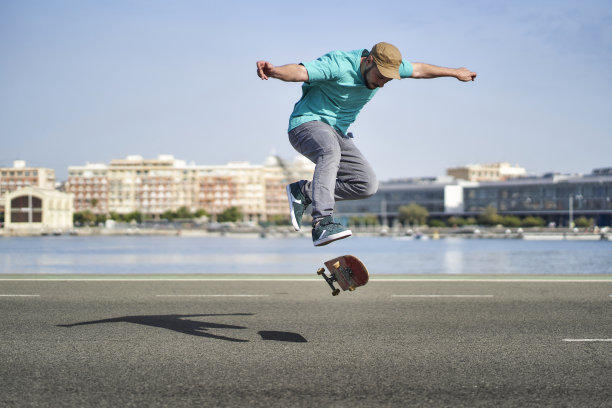 一个男人在马路上玩滑板做360度翻转图片下载