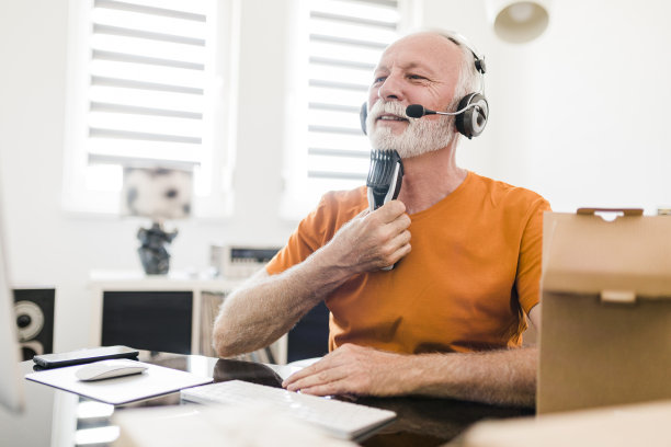 微笑的资深男性社交媒体技术影响力与耳机录制开箱视频在家里图片下载