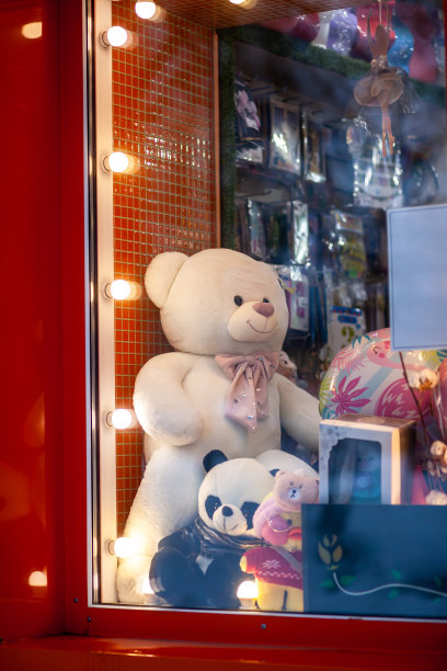 一个大的白色泰迪熊和其他玩具在商店的橱窗里。图片下载