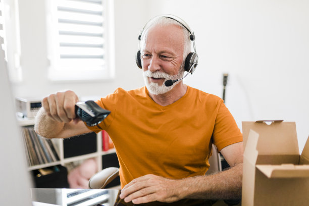 微笑的资深男性社交媒体技术影响力与耳机录制开箱视频在家里图片下载