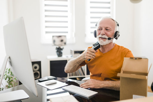 微笑的资深男性社交媒体技术影响力与耳机录制开箱视频在家里图片下载