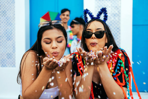 巴西的狂欢节。年轻的女孩们在狂欢派对上吹着五彩纸屑图片下载