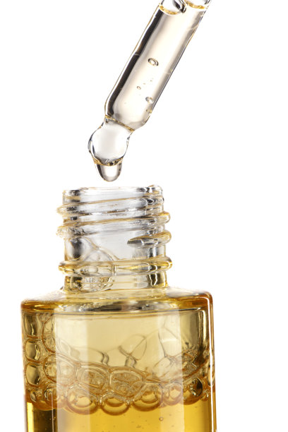 一瓶黄色美容精华液的一部分。化妆品玻璃移液器，白色背景上有黄色油滴血清特写。图片下载