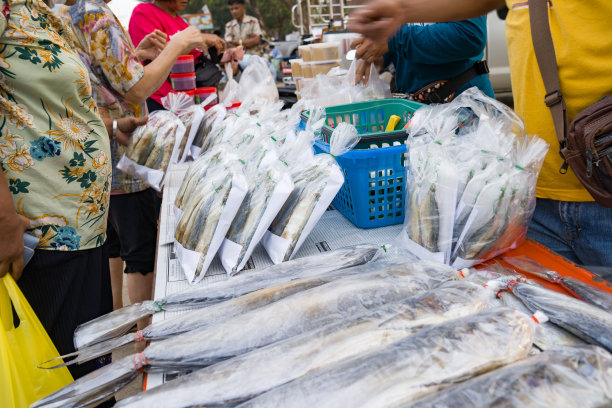 在当地大排档的桌子上，新鲜的鱼装在透明的袋子里，许多顾客都在挑选。图片下载