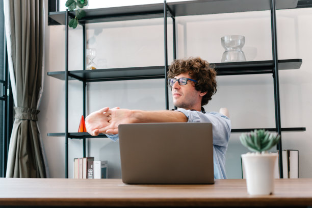 商人用笔记本电脑工作，伸伸懒腰或懒洋洋地放松图片下载