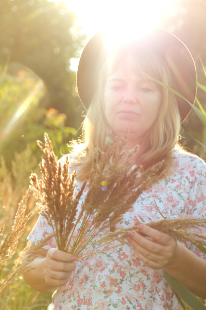 美丽的年轻金发女子在自然背景下的户外特写散焦人像。女子手持一束蒲苇草。心理健康，户外。生活方式，健康，波西米亚风。日落。失焦图片下载