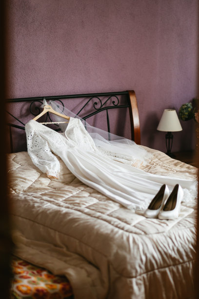 垂直拍摄的婚礼鞋与婚纱在床上。图片下载