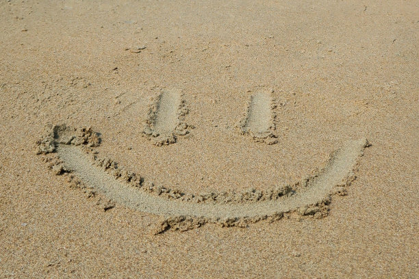 在阳光明媚的海滩上用木棍在潮湿的沙子上绘制笑脸的特写图像，高架视图，专注于前景，假期和度假概念图片下载