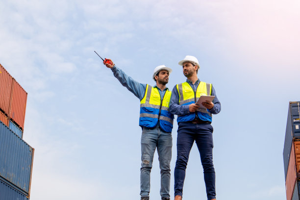 团队商人在集装箱运输公司检查货物，白人工人计划运输货物通过船舶分销商。图片下载