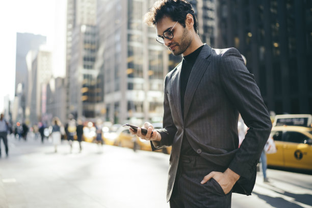 侧视图:穿着正装的欧洲男性企业家站在市中心用智能手机输入短信，成功的经济学家在连接4g的移动应用程序中阅读金融新闻图片下载