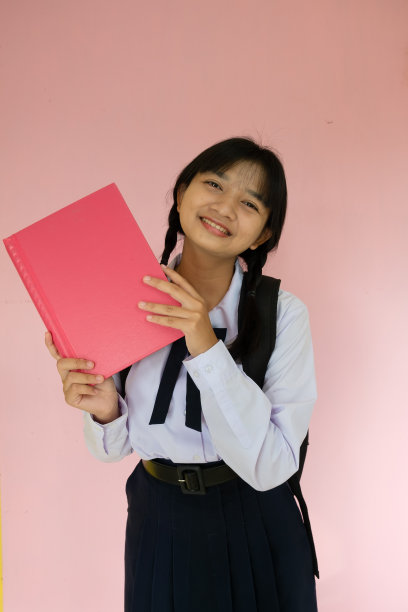 学生女孩的背包和粉红色的书在粉红色的背景。图片下载