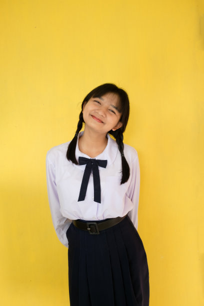 身着黄色背景制服的女学生。图片下载