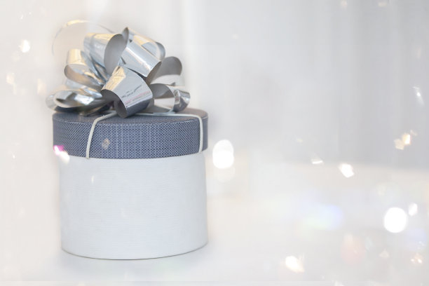 灰色礼盒装饰蝴蝶结在节日的散景背景。图片下载