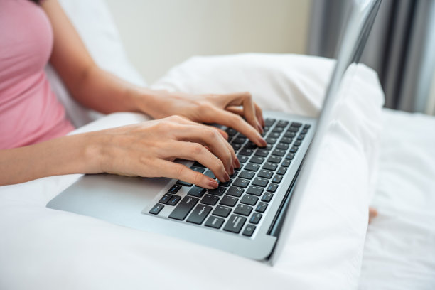 近距离的亚洲年轻女商人打字笔记本电脑键盘在房子。迷人的女孩学生雇员工人坐在床上，使用电脑规划工作项目，在家客厅在线学习图片下载