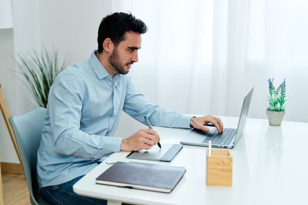 年轻人用记事本和笔记本电脑写字图片下载