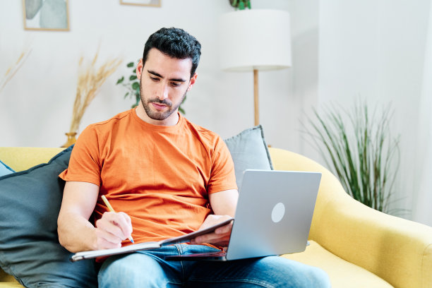 微笑的男人在客厅使用笔记本电脑图片下载