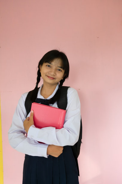 学生女孩的背包和粉红色的书在粉红色的背景。图片下载