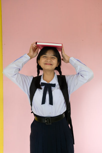 学生女孩的背包和粉红色的书在粉红色的背景。图片下载