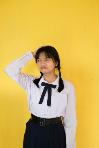身着黄色背景制服的女学生。图片下载