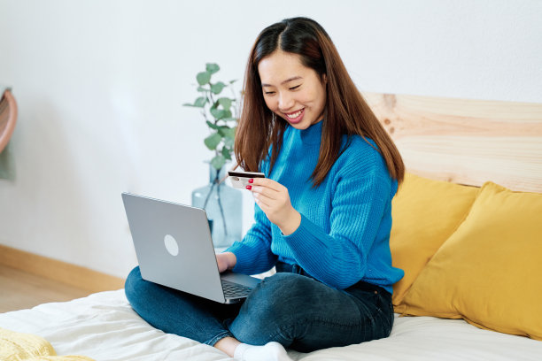 微笑的女人在床上用笔记本电脑网购图片下载