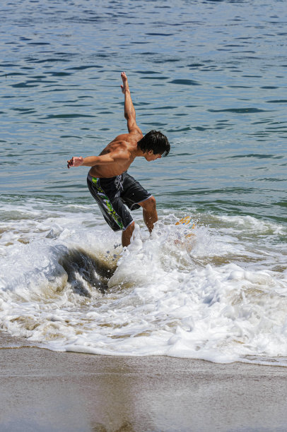 在海浪中玩耍的拉丁裔少年图片下载