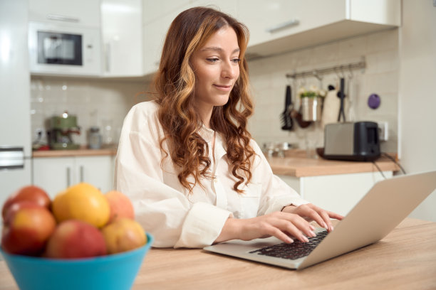 专注的女性在厨房使用便携式电脑图片下载