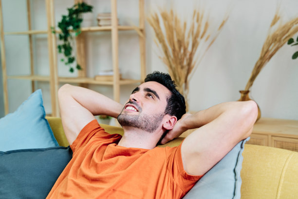 开朗的男人躺在客厅的沙发上图片下载