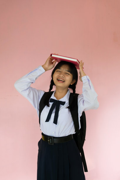 学生女孩的背包和粉红色的书在粉红色的背景。图片下载