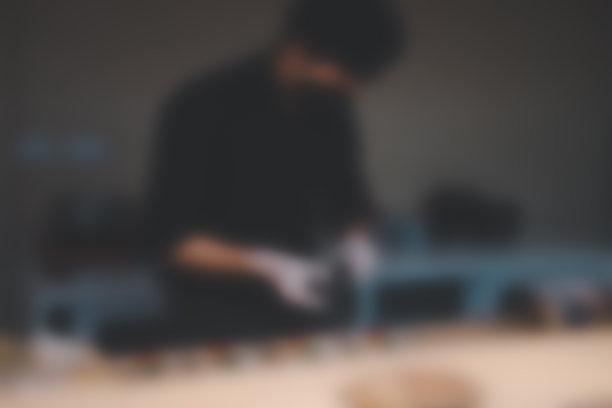 背景模糊的厨师穿着制服，戴着黑色面罩烹饪食物。图片下载