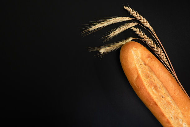新鲜的面包和干小麦在黑色的背景。从上面的观点图片下载