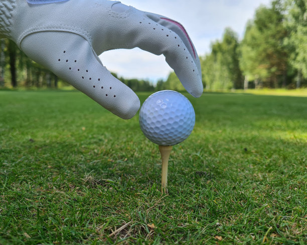 手握高尔夫球的特写。手握高尔夫球在高尔夫球座上图片下载