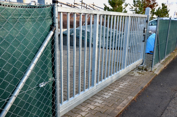 通过一个低矮的滑动门进入院子到停车场。大门沿着栏杆横向移动。柱子上有一个橙色闪烁的信标。遥控器打开滑动门图片下载